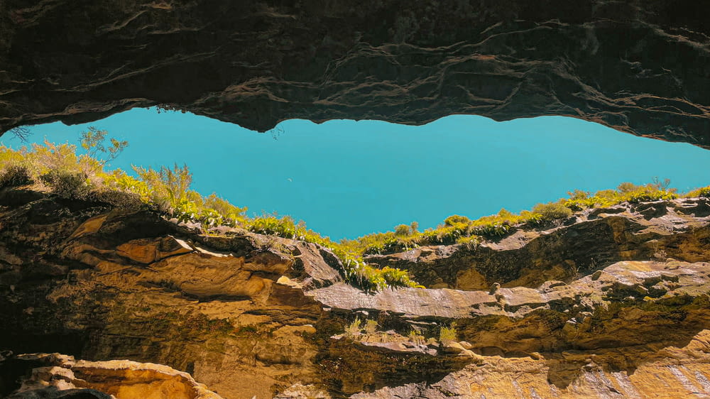 a blue lake is seen from inside a cave