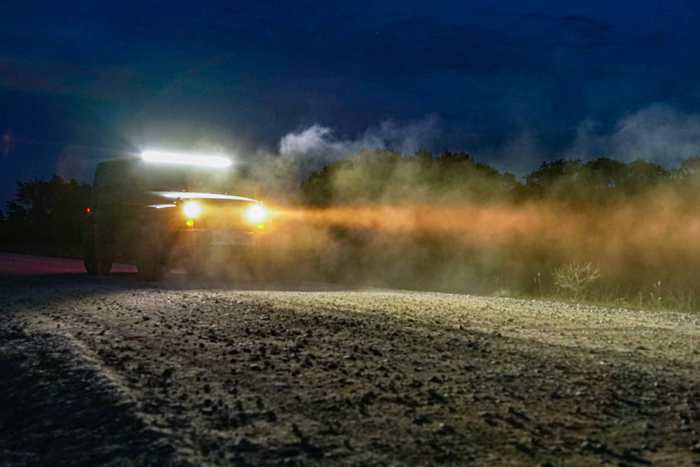 a truck driving down a dirt road at night