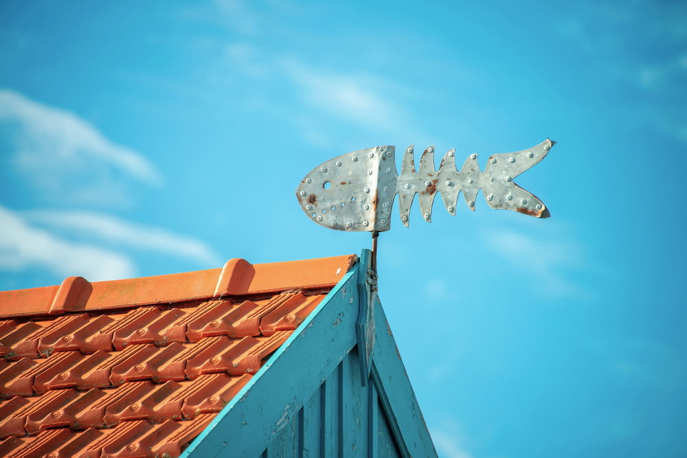a metal fish sign on top of a roof