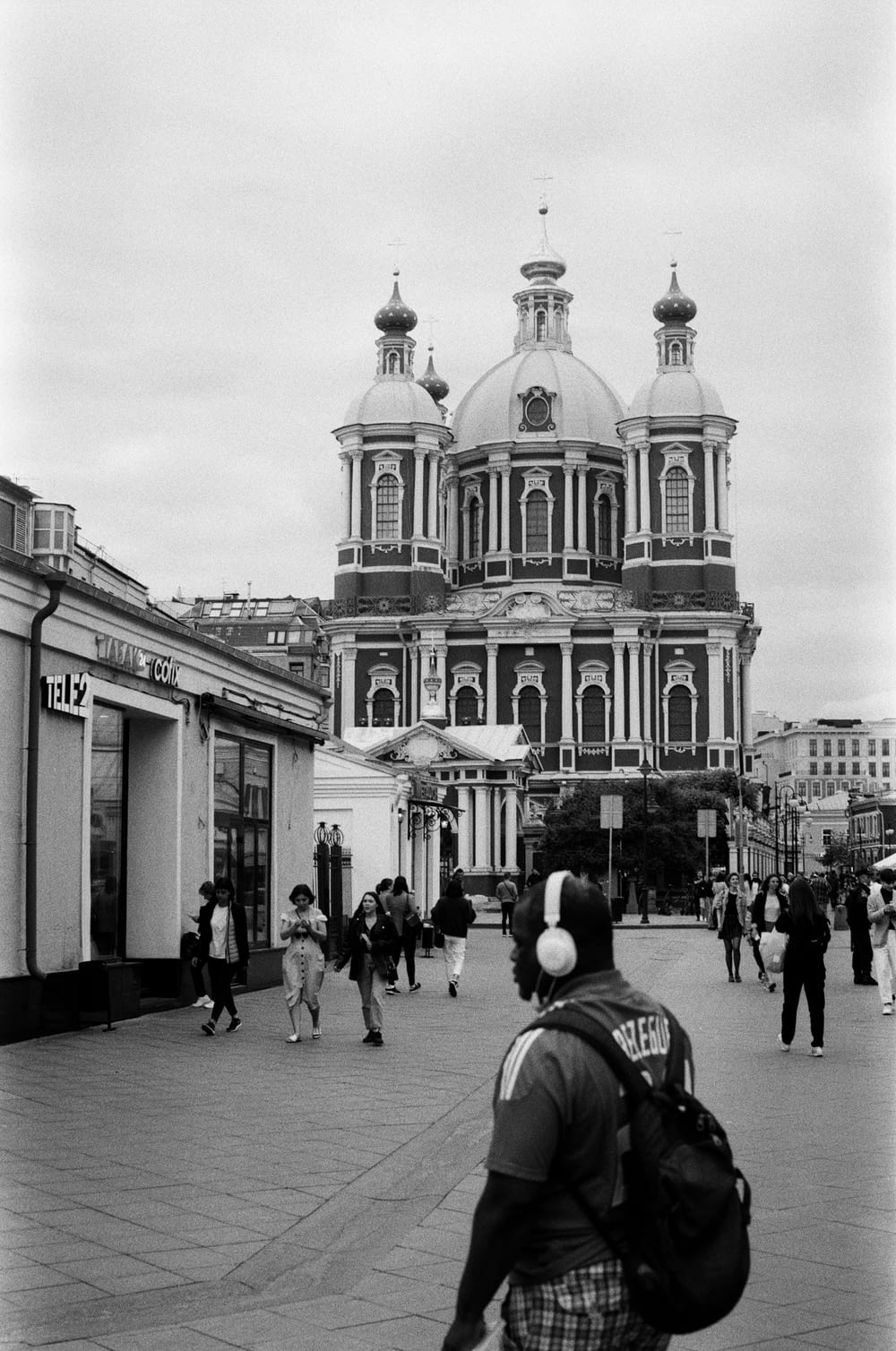 a black and white photo of a man walking in front of a building