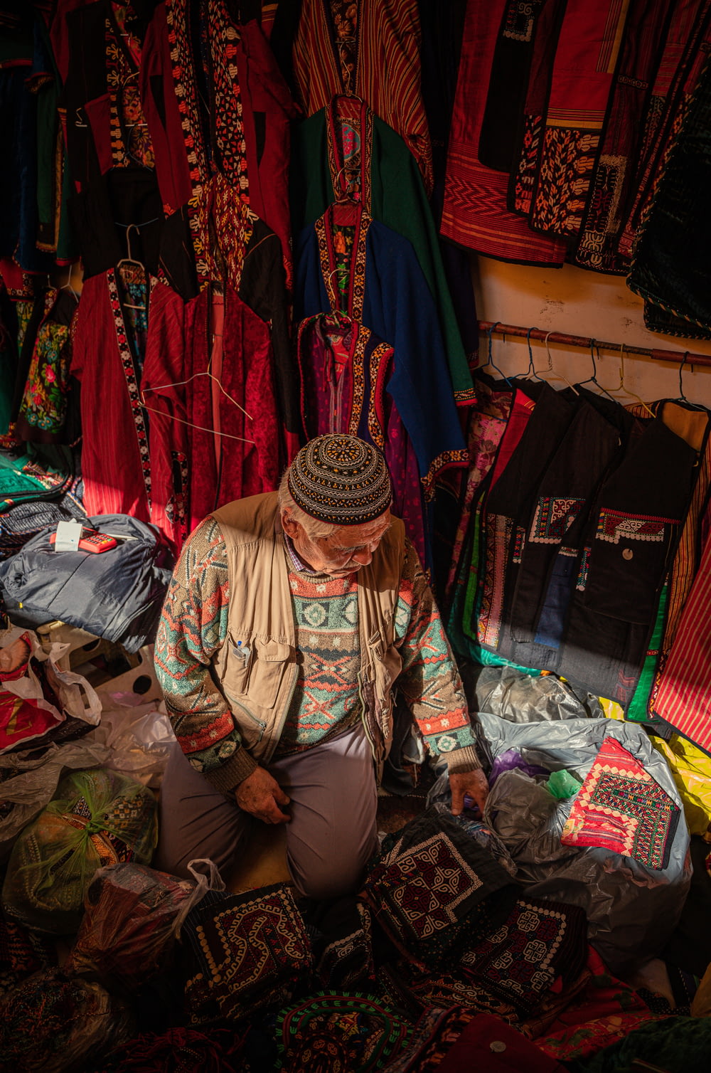 a man sitting on the ground in front of a pile of clothing