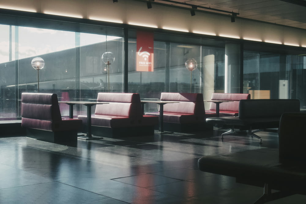 una zona d'attesa con sedie e tavolini davanti ad ampie vetrate