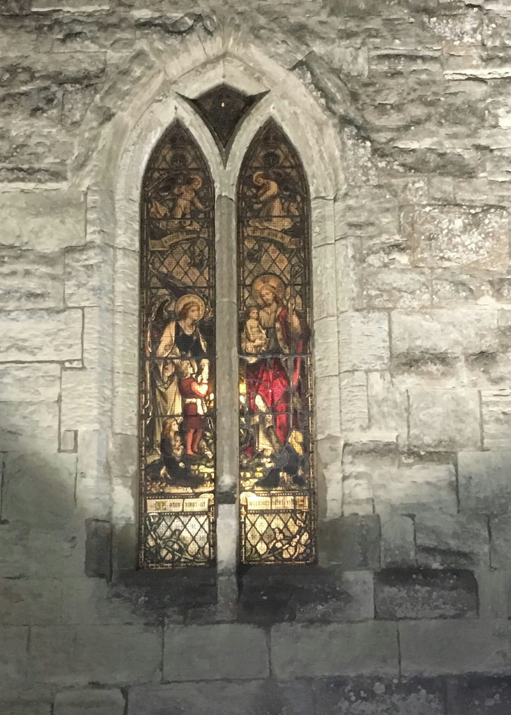 two stained glass windows in a stone wall