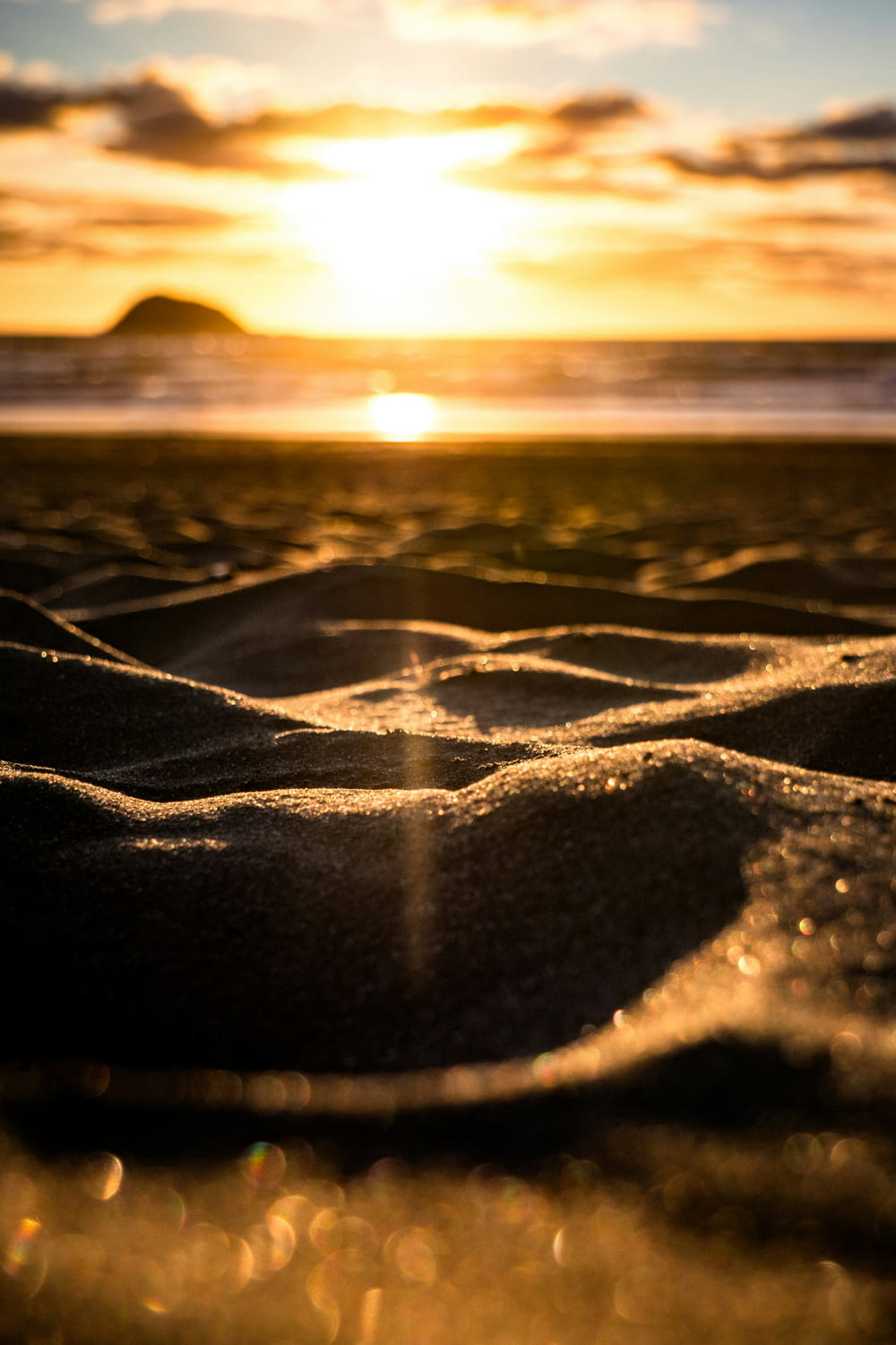 el sol se está poniendo sobre la playa y la arena