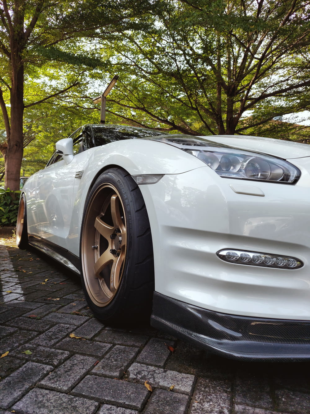 a white sports car parked in front of a tree