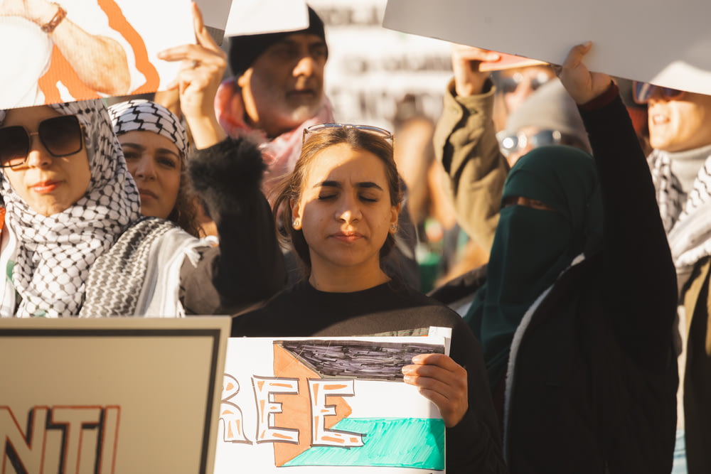 a group of people holding signs and wearing headscarves