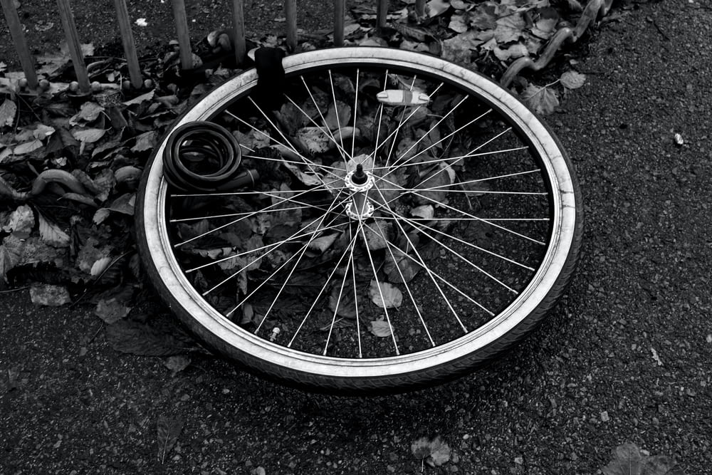 a bicycle wheel laying on the ground next to a fence