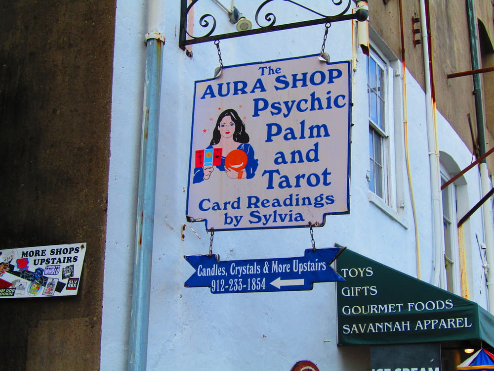 a sign on the side of a building that says aura shop psychic palm and tar