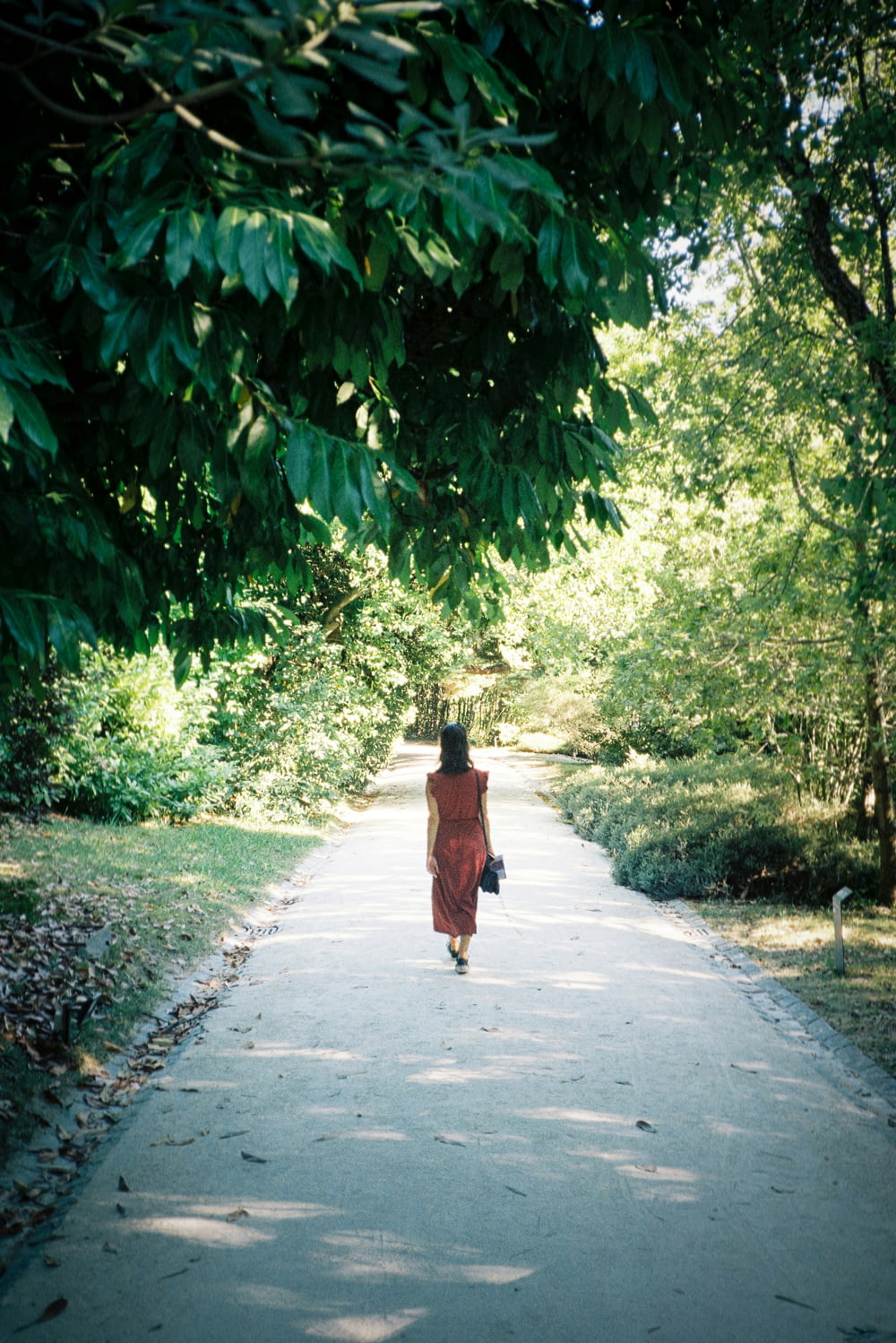a woman in a red dress walking down a path