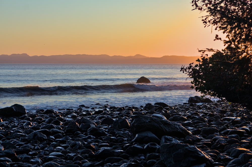 太陽が海に沈み、海岸には岩が置かれています