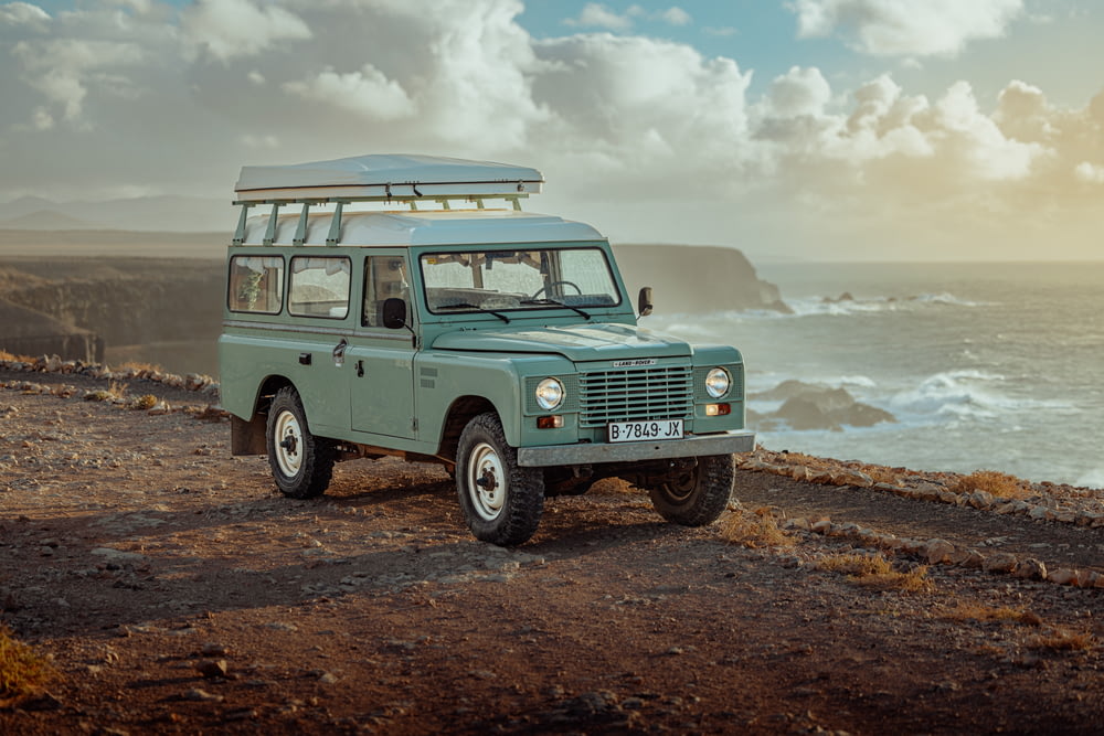 a green land rover parked on the side of the road