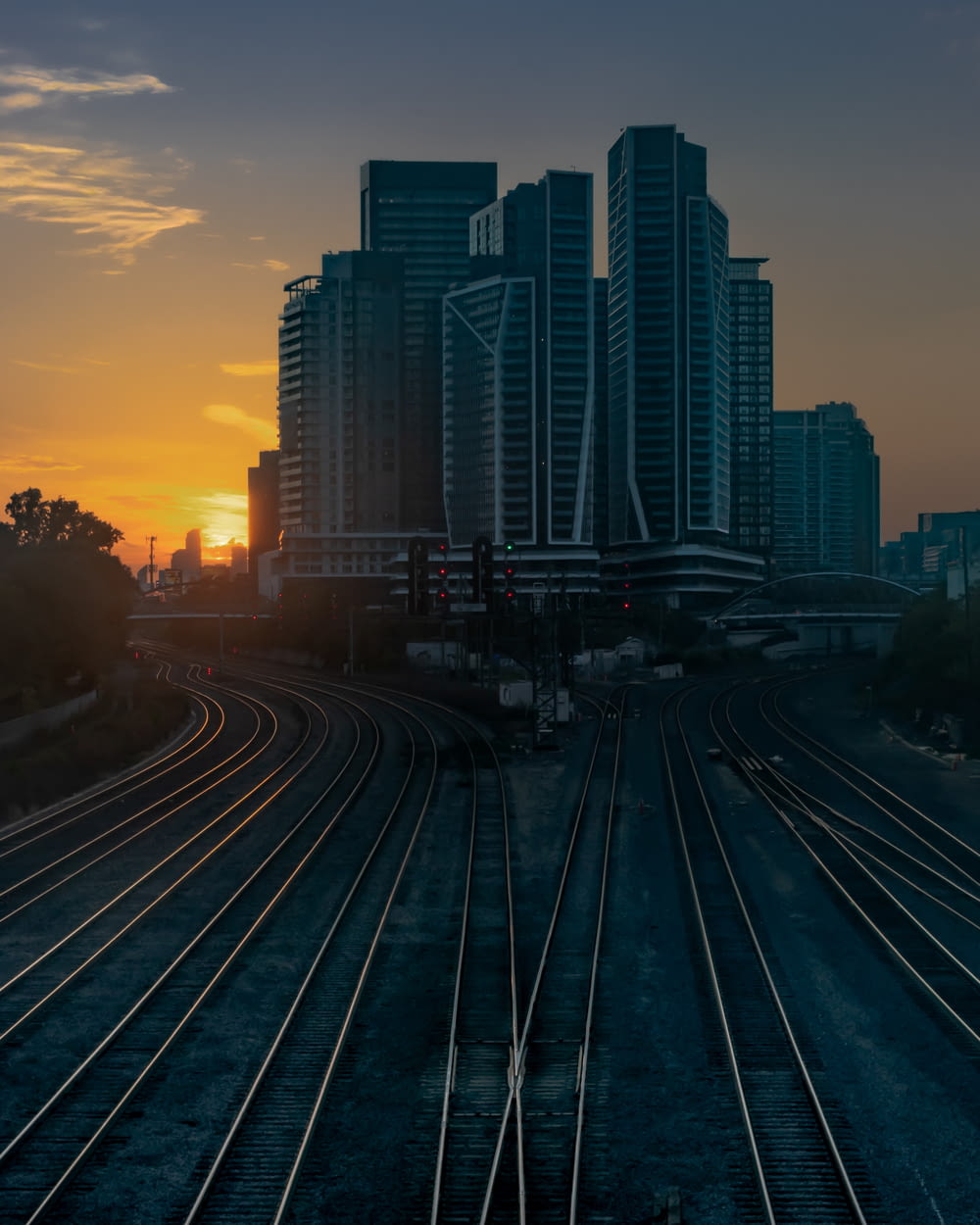 a sunset view of a train track with buildings in the background