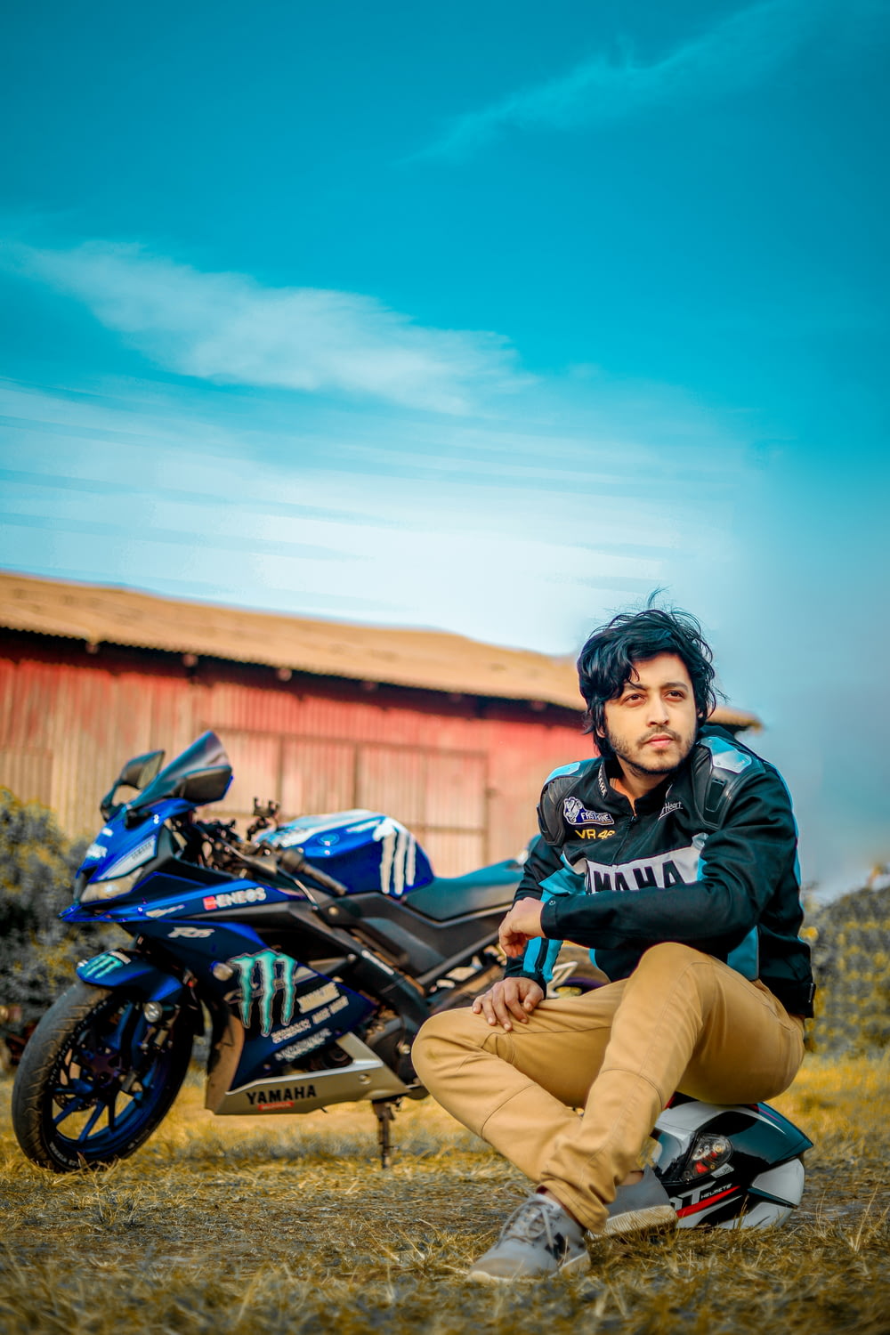 a man sitting on the ground next to a motorcycle