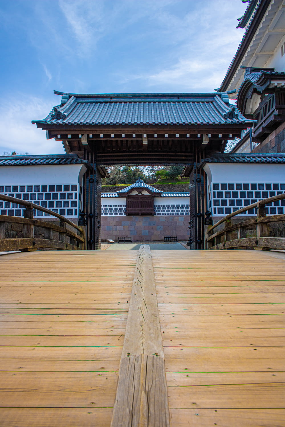 a wooden walkway leading to a building with a blue roof