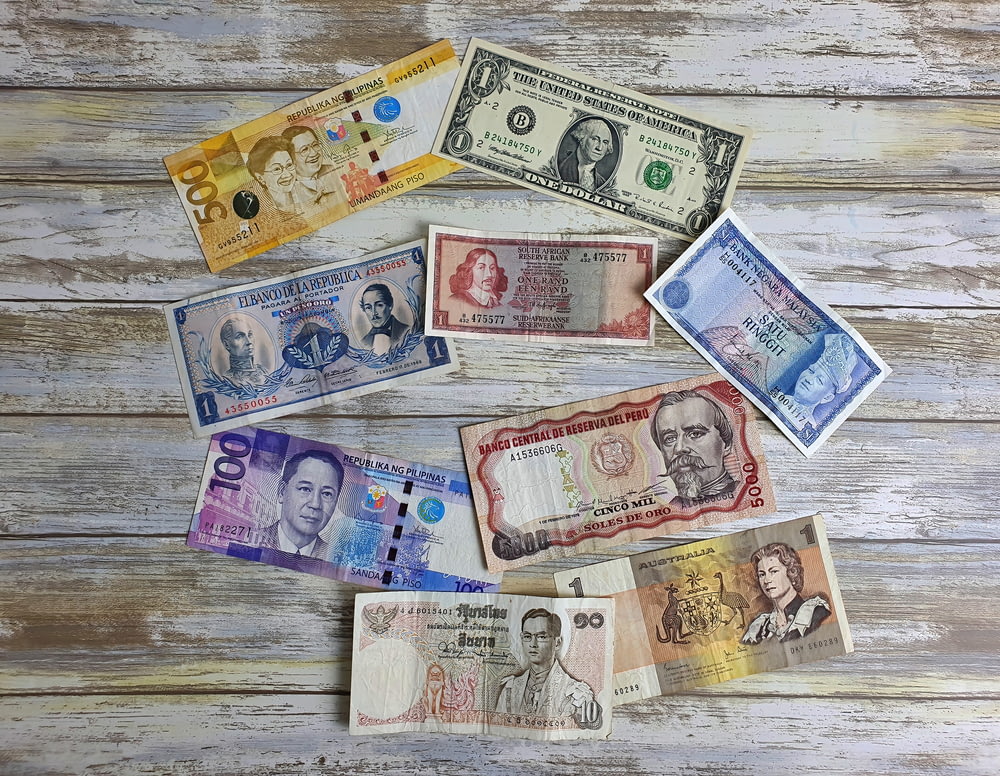 a bunch of different currency sitting on top of a wooden table