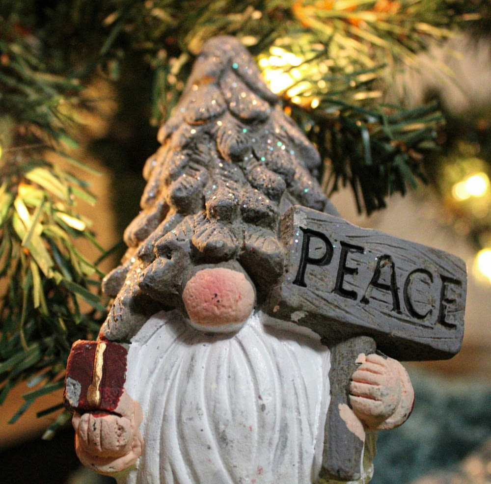 a statue of a gnome holding a sign that says peace