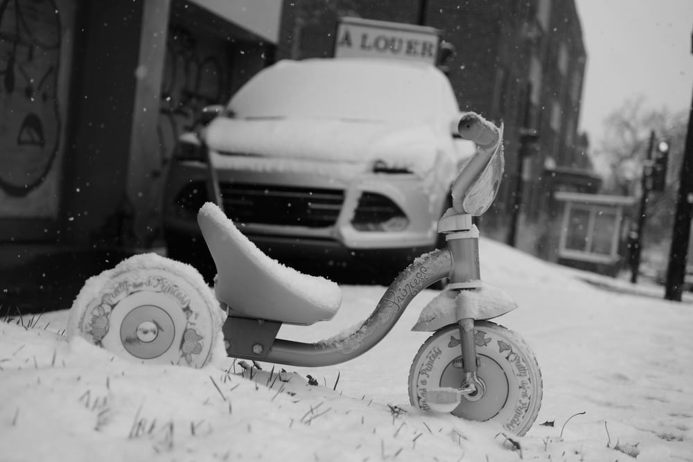 a scooter covered in snow next to a car