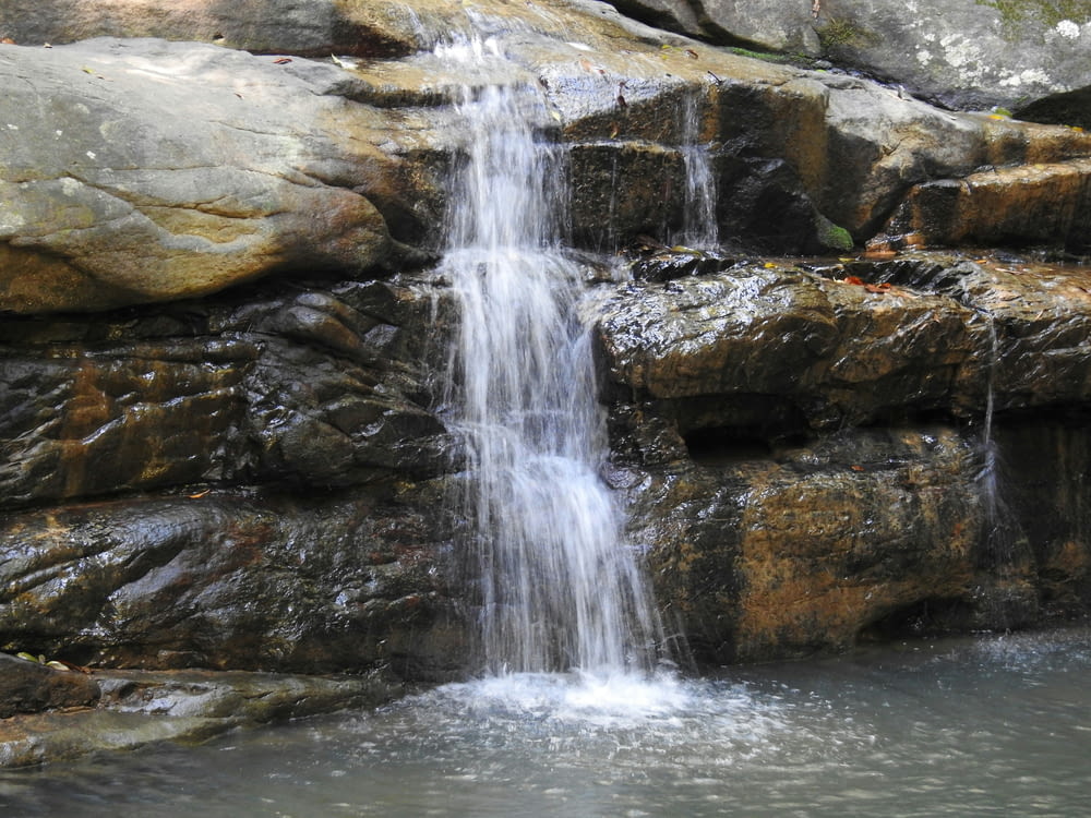 a small waterfall in the middle of a pool of water