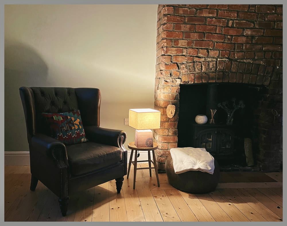a living room with a chair a lamp and a fire place