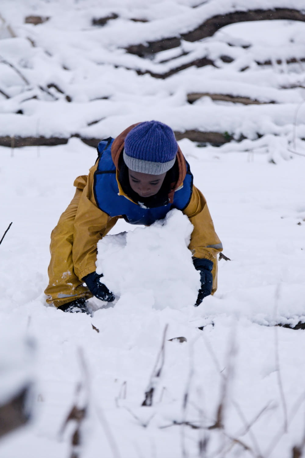 a young boy building a snowman in the snow