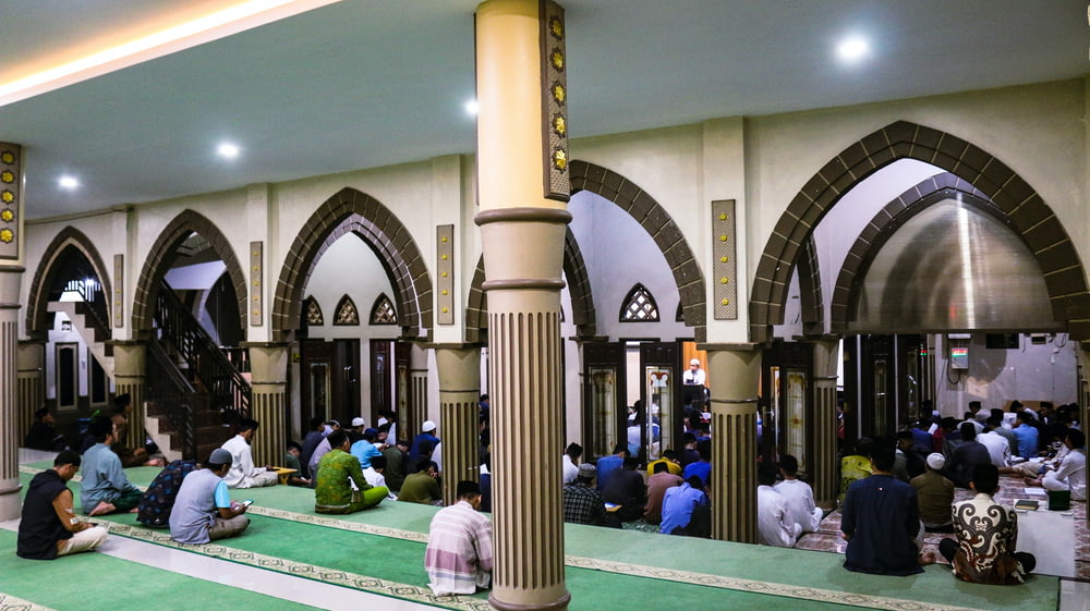 a group of people sitting on the floor of a mosque