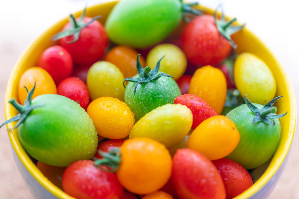 a yellow bowl filled with lots of different colored tomatoes