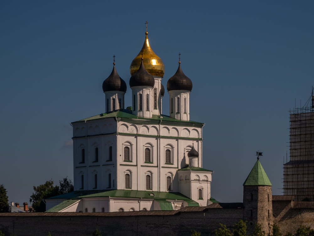a large white and green building with gold domes