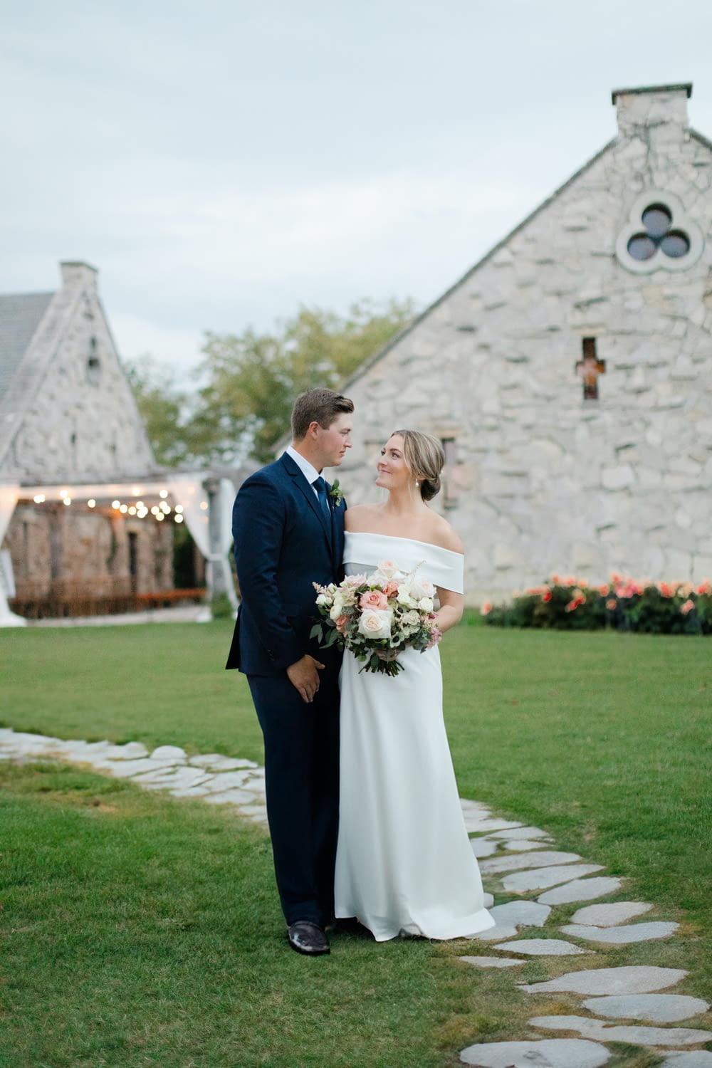 a bride and groom standing in front of a stone building
