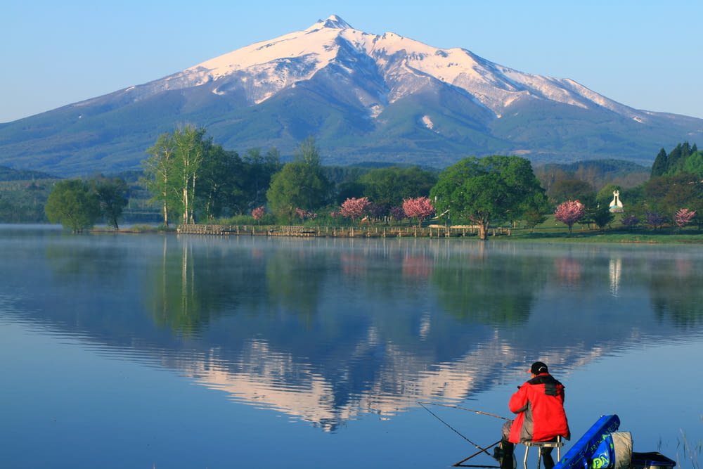 a man fishing on a lake with a mountain in the background