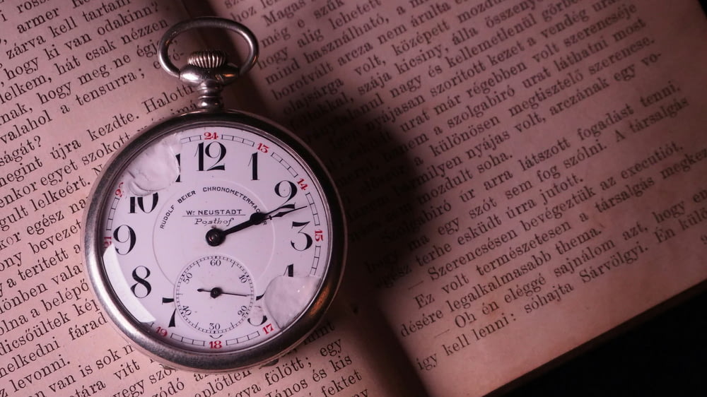 a pocket watch sitting on top of an open book