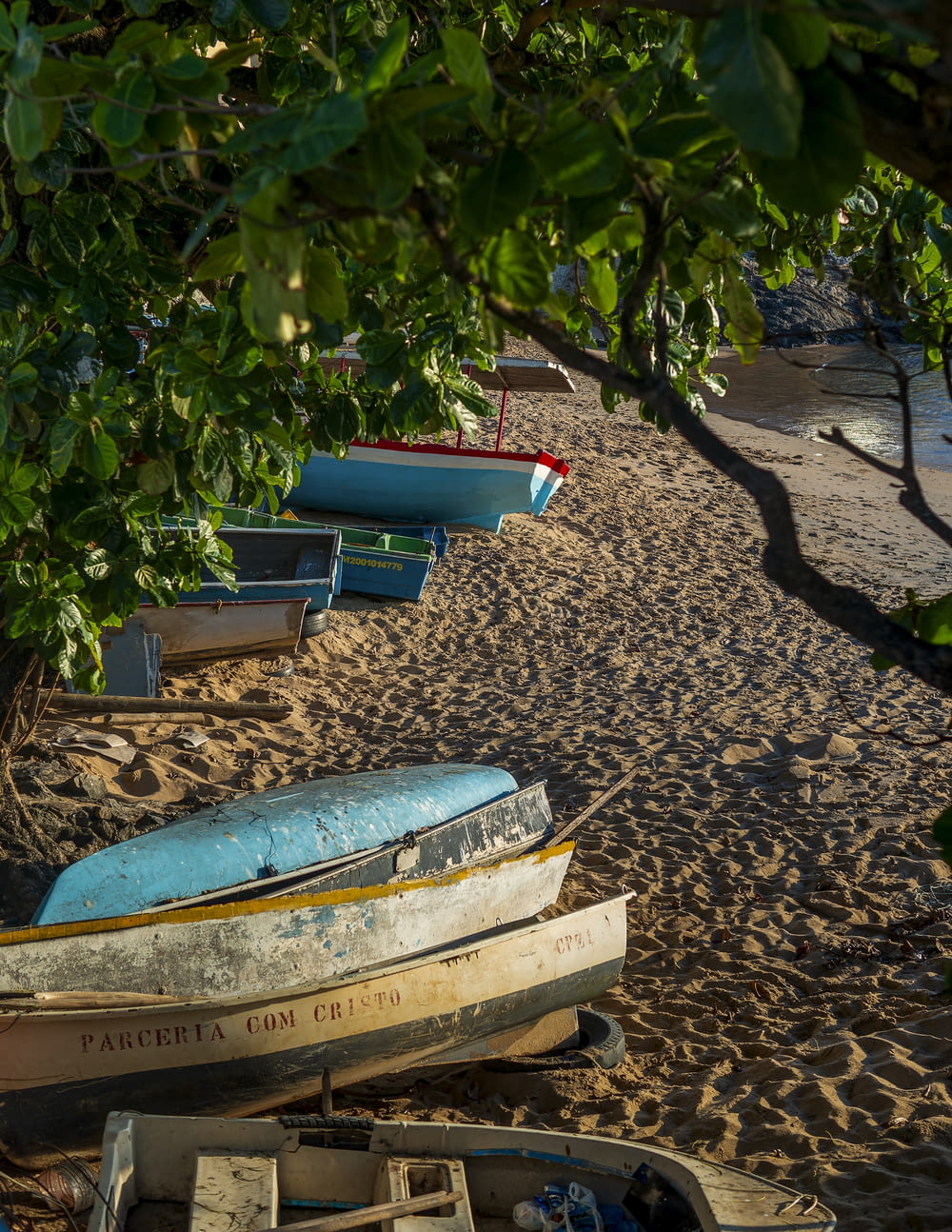 a row of boats sitting on top of a sandy beach
