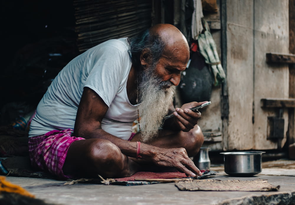 a man sitting on the ground looking at his cell phone