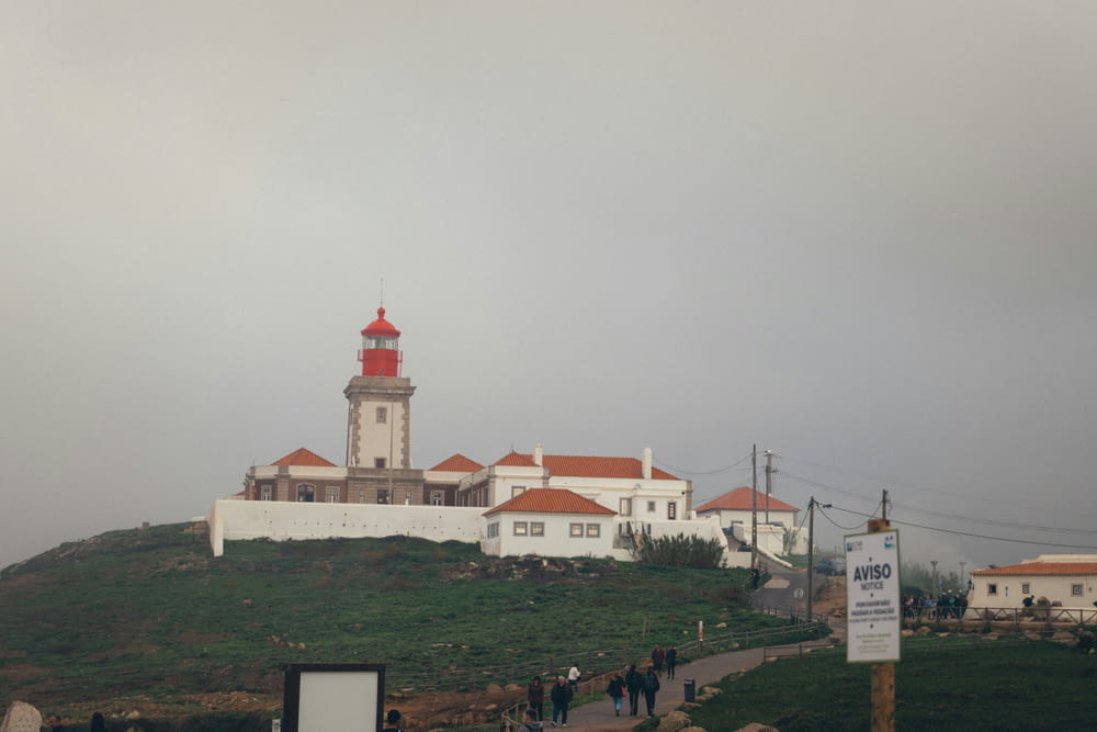a group of people walking up a hill towards a lighthouse