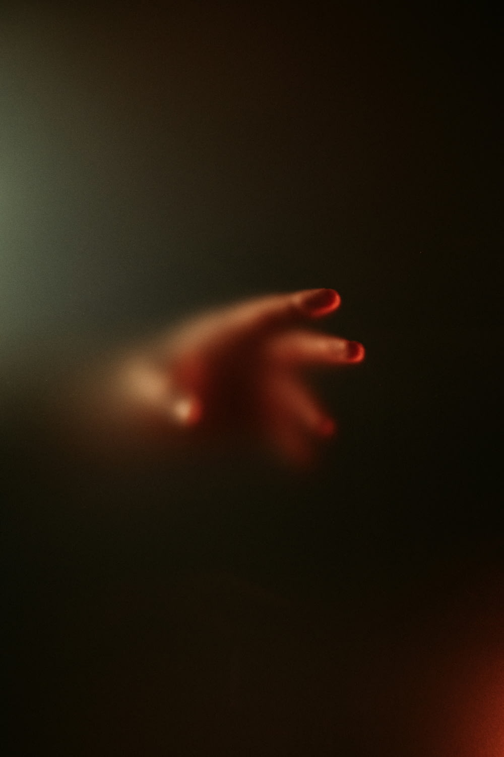 a blurry image of a person's hand with red nails