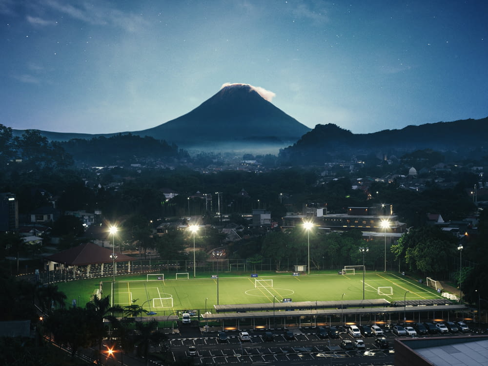 a soccer field at night with a mountain in the background