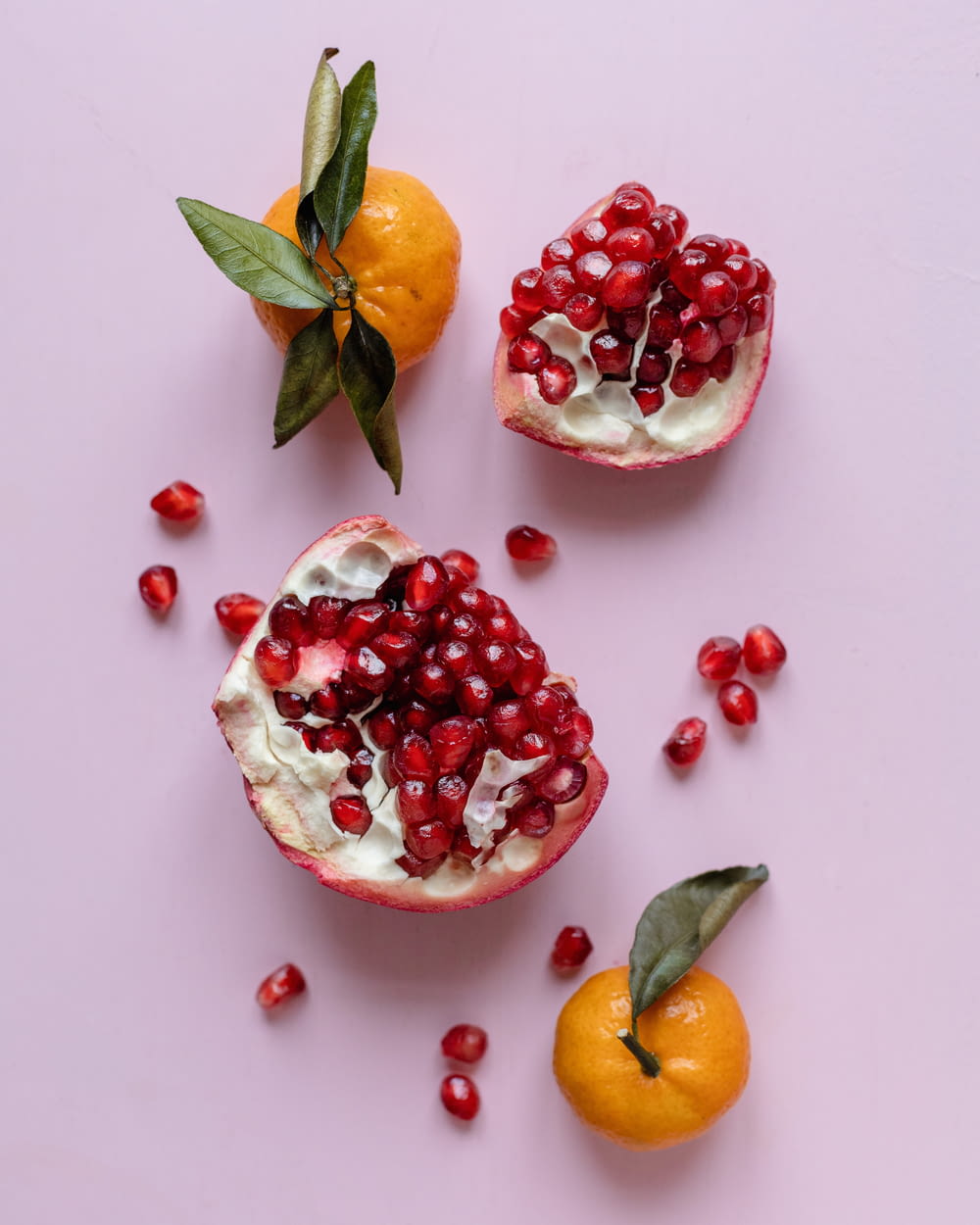 pomegranates and oranges on a pink surface