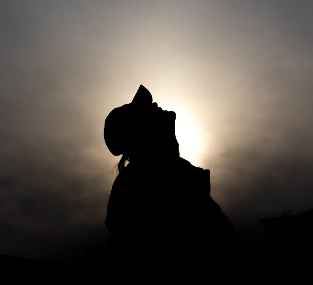 a silhouette of a person with a hat on