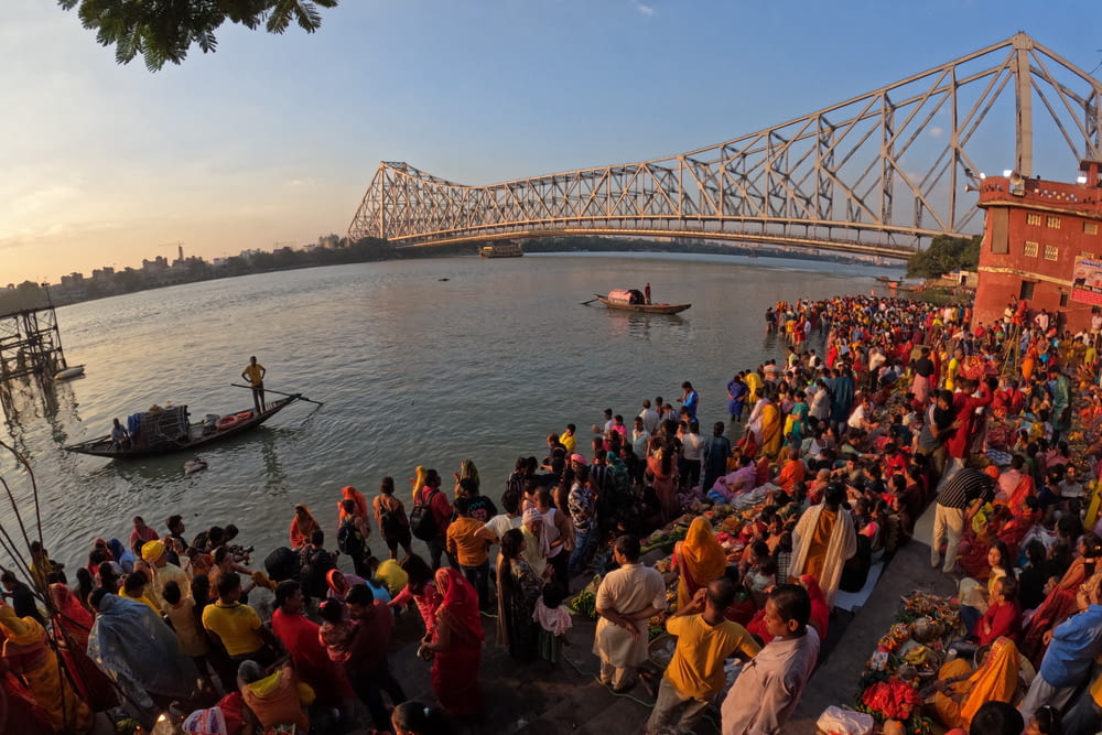 a crowd of people standing on the side of a river