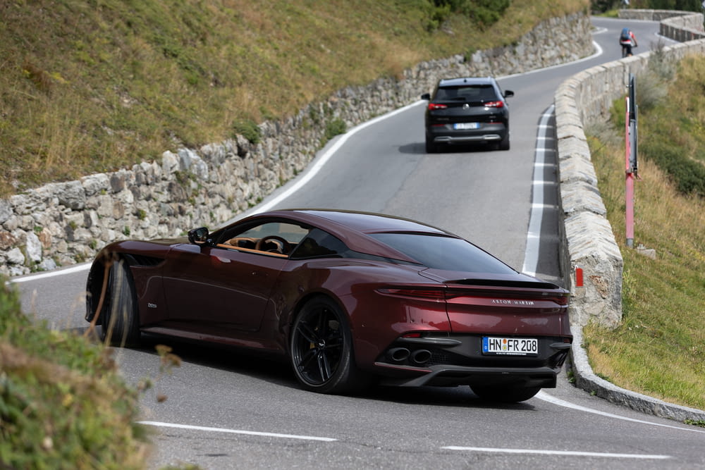 a maroon sports car driving down a winding road