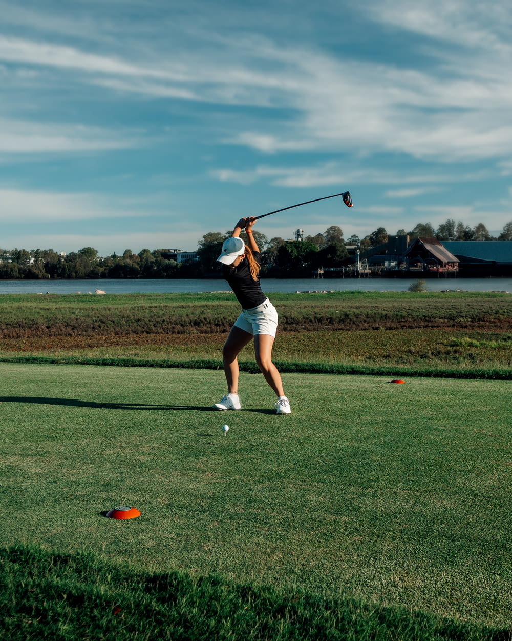 a woman swinging a golf club on top of a green field