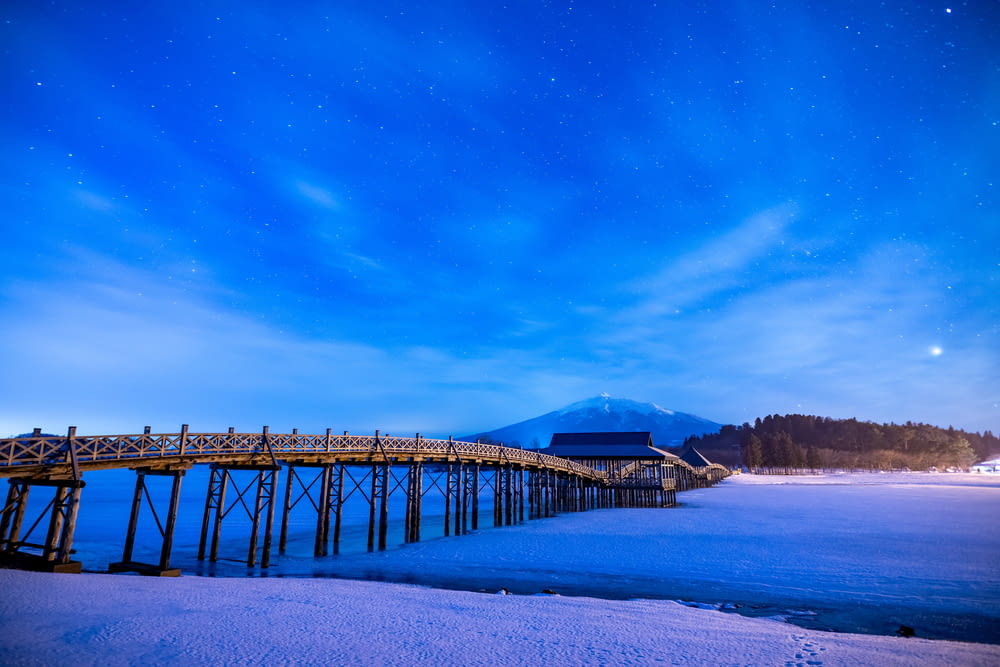 a long wooden bridge over a body of water under a night sky