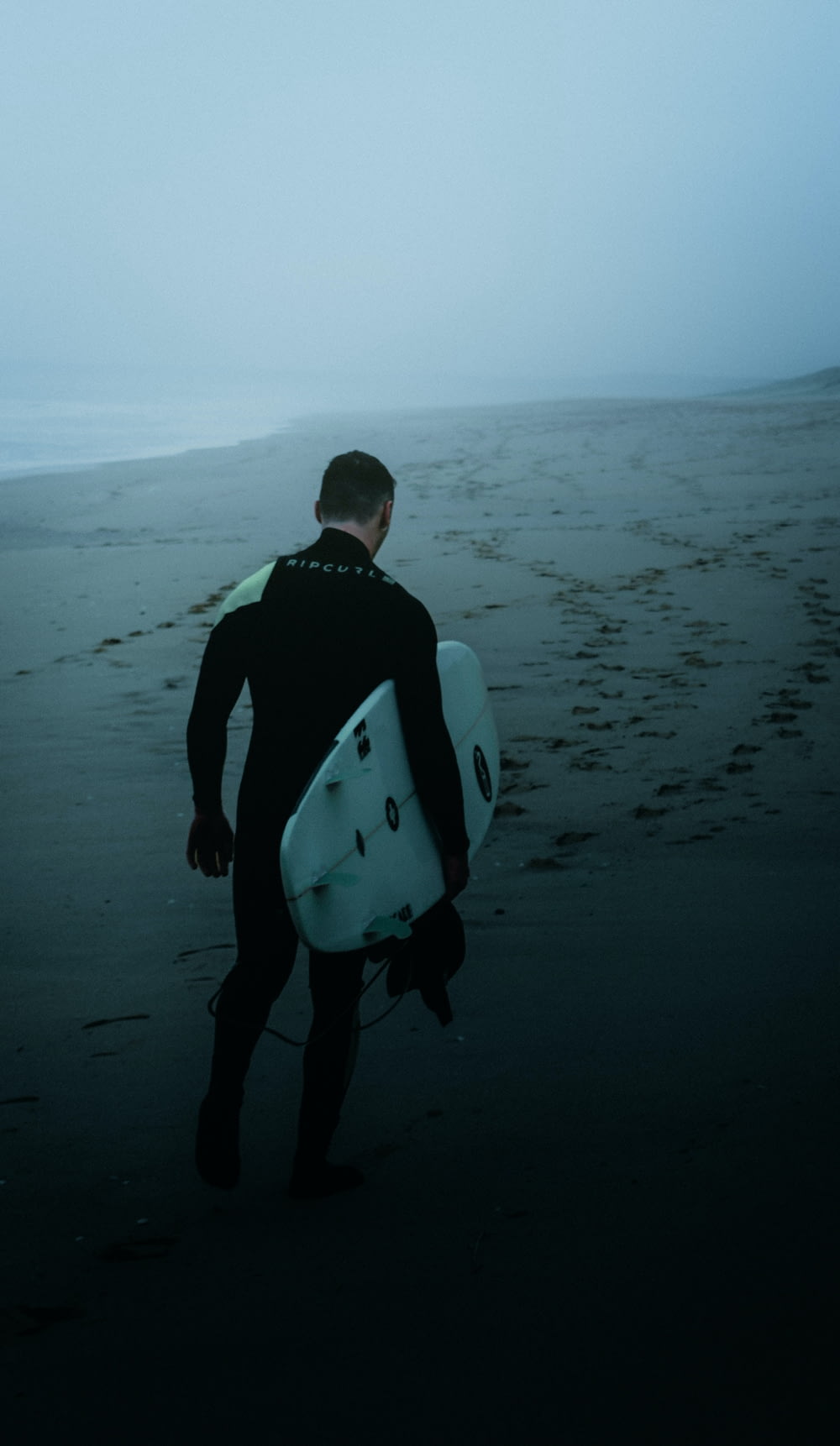 a man in a wet suit carrying a surfboard