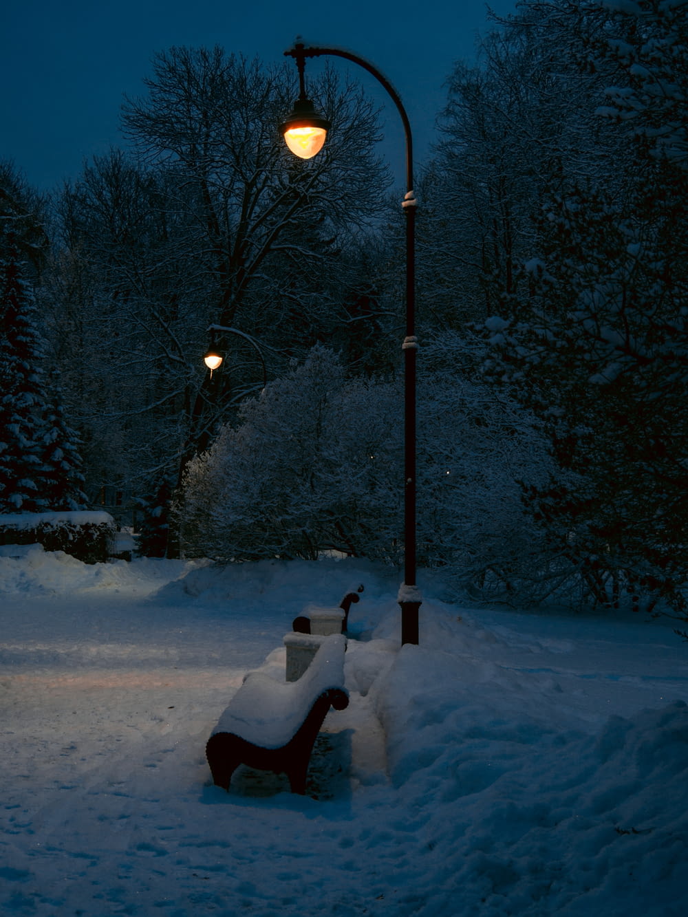 un banc recouvert de neige sous un lampadaire