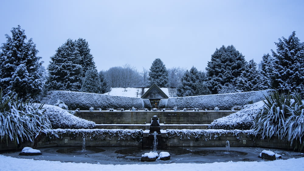 a snow covered garden with a fountain in the middle