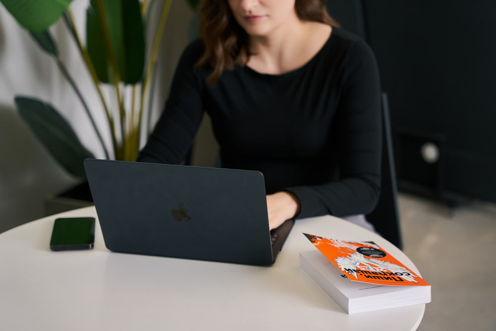 Una mujer sentada en una mesa con una computadora portátil
