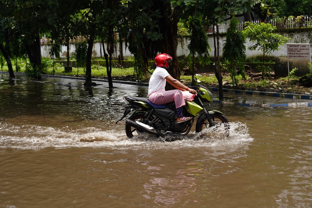 a man riding a motorcycle through a flooded street