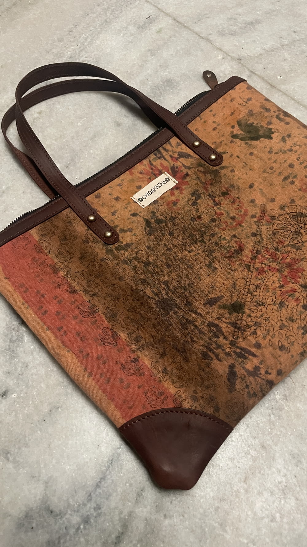 a brown and tan purse sitting on top of a marble floor