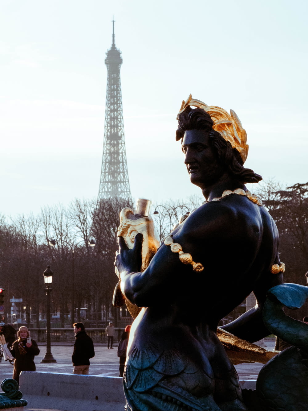 a statue of a woman holding a cat in front of the eiffel tower