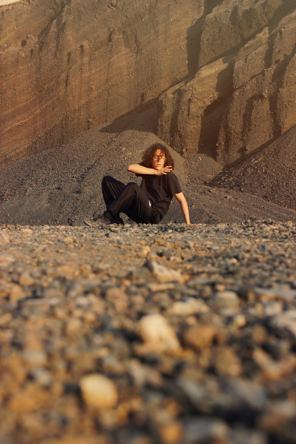 a woman sitting on the ground in front of a mountain
