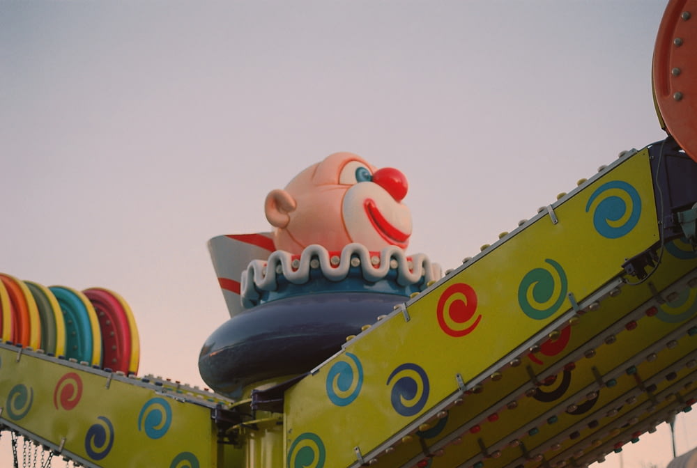 a close up of a carnival ride with a clown hat on top